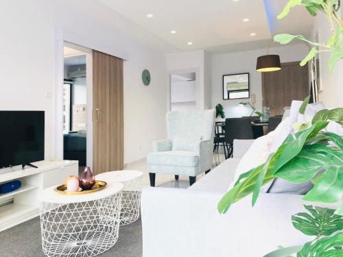 a living room with white furniture and a tv at Metro Court Apartments in Limassol