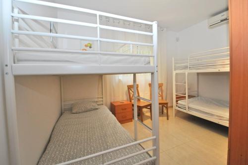 ein Zimmer mit zwei Etagenbetten und einem Tisch in der Unterkunft Villa Genova in Lloret de Mar
