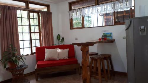 una sala de estar con una silla roja y un bar en Babilonia, en Cahuita