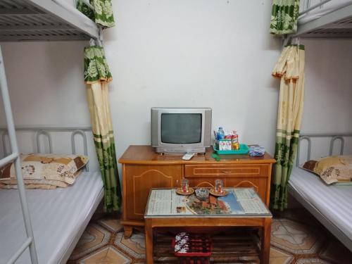 a room with two bunk beds and a tv on a table at Cuc Phuong Hao Tham Homestay Hotel in Phủ Nho Quan