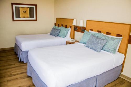 2 bedden in een hotelkamer met witte en blauwe kussens bij Hotel Mirabel in Querétaro