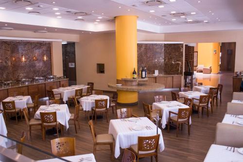 un restaurante con mesas y sillas blancas y un bar en Hotel Mirabel en Querétaro