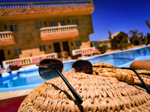 a pair of sunglasses sitting on top of a wicker chair near a pool at Ciao Hotel in Nuweiba