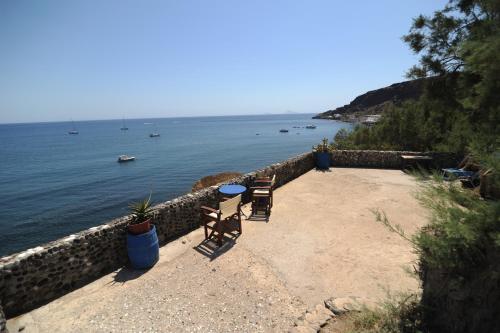 a patio with two chairs and a table next to the water at Akrotiri Hotel in Akrotiri