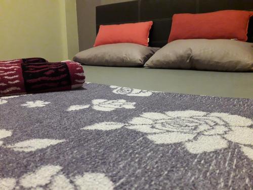 a gray rug with flowers on it next to two pillows at QuiikCat in Kuching