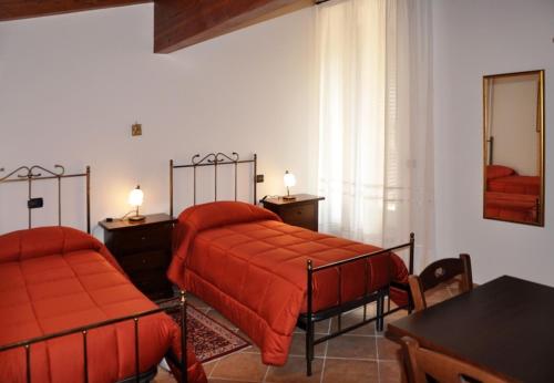 a bedroom with two beds with red sheets and a table at Antica Interamnia in Teramo