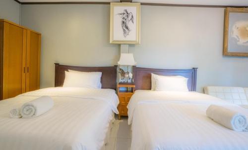 two beds in a room with white sheets at Ban Mai Vintage in Pak Chong