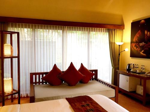 a bedroom with a bed with red pillows and a window at Villa with private pool at Villa Nirvana Ubud in Ubud