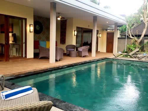 a swimming pool with wicker chairs and a patio at Villa with private pool at Villa Nirvana Ubud in Ubud