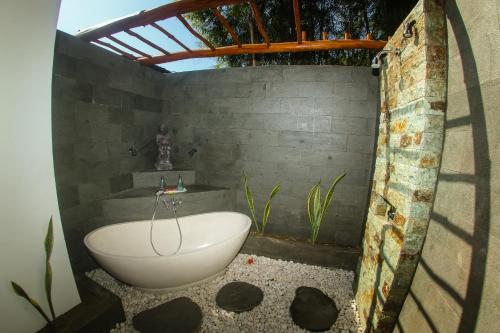a bathroom with a bath tub and a sink at Flower Bud Bungalow Balangan in Jimbaran
