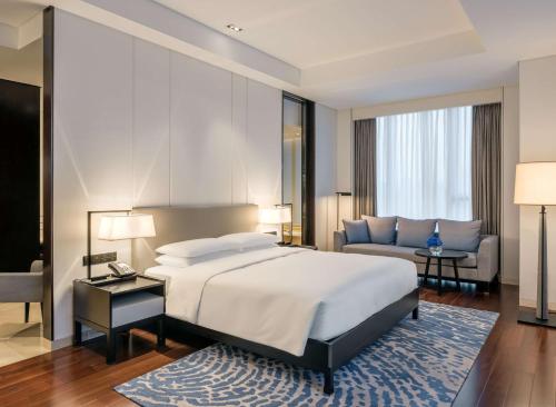 a bedroom with a king sized bed and a couch at Hyatt Regency Shanghai Global Harbor in Shanghai