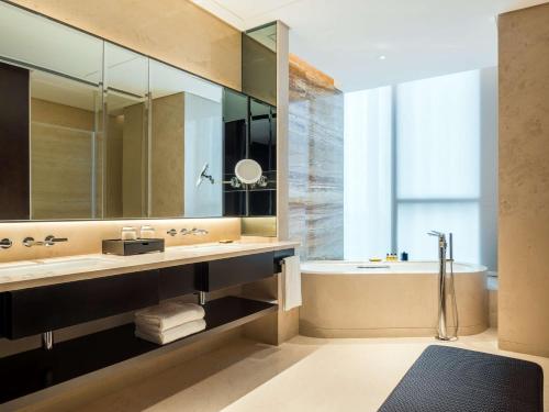 a bathroom with a large mirror and a tub and a sink at Hyatt Regency Shanghai Global Harbor in Shanghai
