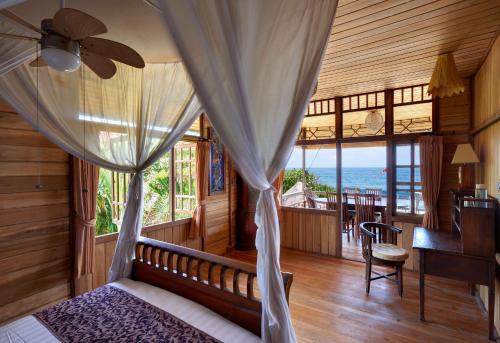 a bedroom with a bed with a ceiling fan and a desk at Jasri Bay Hideaway in Jasri