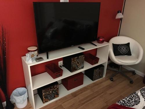 a television on a white entertainment center with a chair at The Haven at Charity House in Waldorf