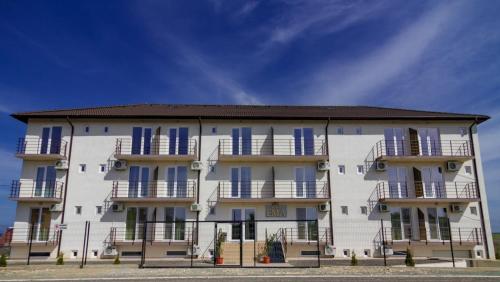 a large white building with blue windows and balconies at Ema in Vama Veche
