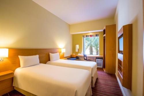 a hotel room with two beds and a window at ibis Mall Avenue Dubai in Dubai
