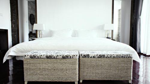 a bedroom with a large bed with two wicker seats at Qingxin Courtyard Art Guesthouse in Dali