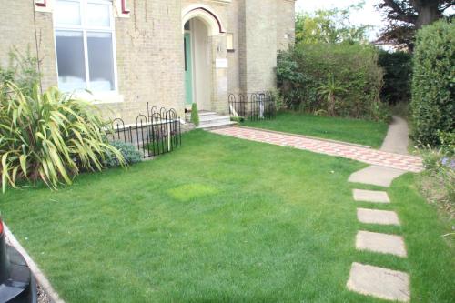 a garden with a brick walkway in front of a house at The Kenbury B&B in Shanklin