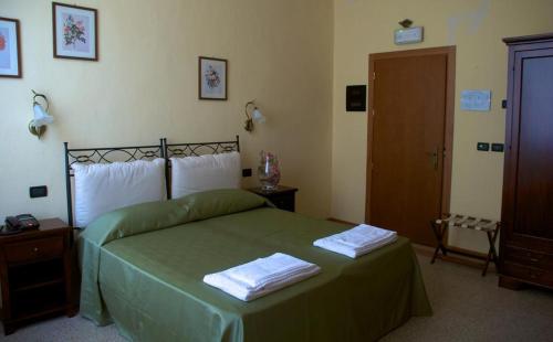 a bedroom with a green bed with two towels on it at Il Convento in Trino