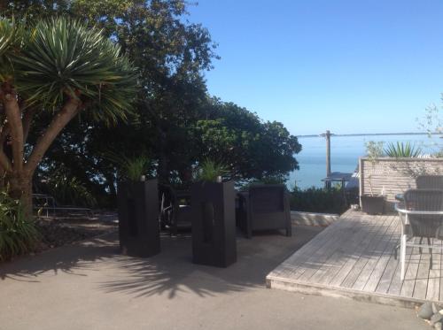 a patio with plants in trash cans next to the ocean at Mason lane Apartment in Whangarei