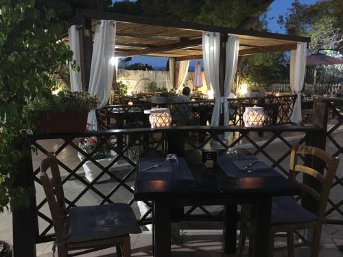 a restaurant with tables and chairs under a pergola at Affittacamere la Medusa in Porto Pino