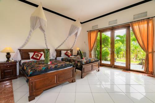 a bedroom with two beds and a large window at Pondok Wisata Sartaya 2 in Lovina