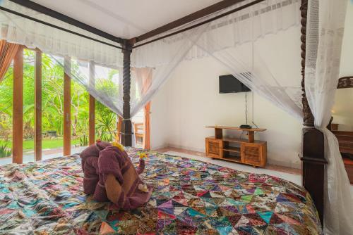 a bedroom with a bed with a teddy bear on it at Pondok Wisata Sartaya 2 in Lovina