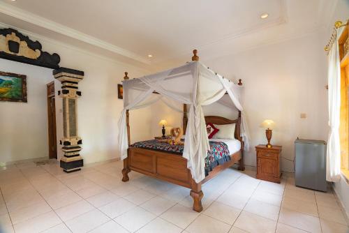 a bedroom with a bed with a canopy at Pondok Wisata Sartaya 2 in Lovina