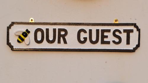 a sign that says our guest with a bee on it at Nettleton Country House in Nettleton