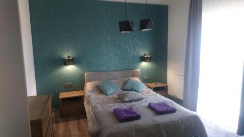 a bedroom with a bed with purple pillows on it at Apartamenty 5 mórz in Sianozety
