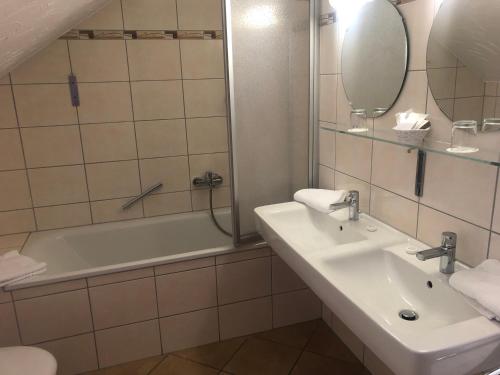 a bathroom with a sink and a tub and a mirror at Hotel & Gastropark Loemühle in Marl