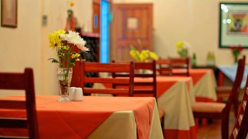 a dining room with tables and chairs with orange tables and flowers at Kashana Namibia in Omaruru