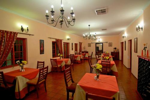 a restaurant with red tables and chairs and a chandelier at Kashana Namibia in Omaruru