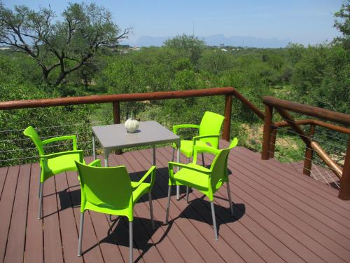 a wooden deck with a table and chairs on it at Woodpecker Lodge B&B in Hoedspruit