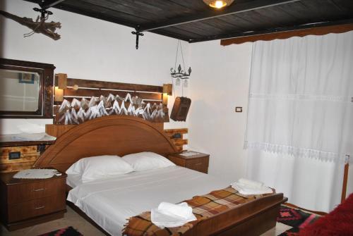 a bedroom with a large bed with a wooden headboard at Guesthouse Mele in Gjirokastër