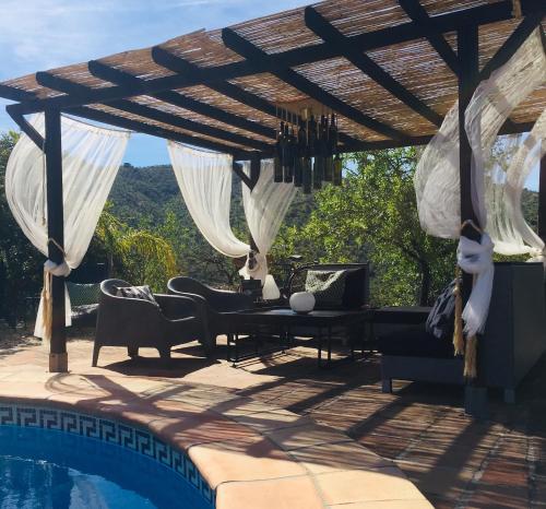 un patio con una pérgola de madera y una piscina en B&B Sol y Monte, en Álora