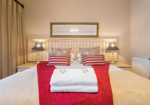 a bedroom with a large bed with red and white blankets and pillows at Caledon 23 Country House in George