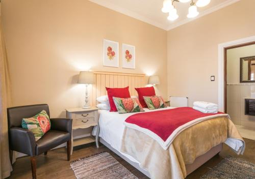 a bedroom with a bed with red pillows and a chair at Caledon 23 Country House in George