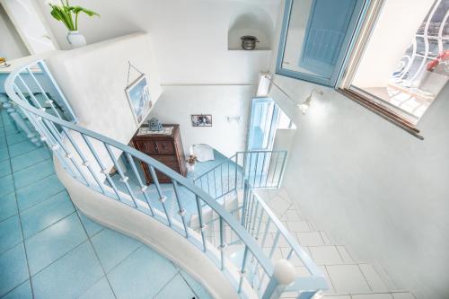 a spiral staircase in a house with white walls and blue floors at Casa Athina in Procida