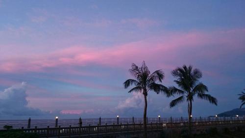 two palm trees in front of the ocean at dusk at 36 Lighthouse in Hualien City