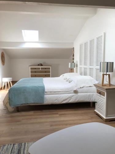 ein weißes Schlafzimmer mit einem großen Bett und einem Tisch in der Unterkunft Bellevue in Saintes-Maries-de-la-Mer