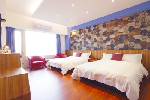 a hotel room with two beds and a chair at 36 Lighthouse in Hualien City
