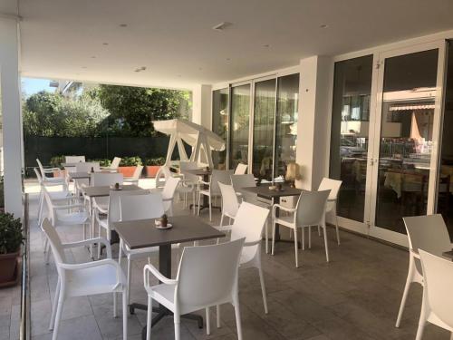 a restaurant with white chairs and tables and windows at Pensione Elena in Misano Adriatico