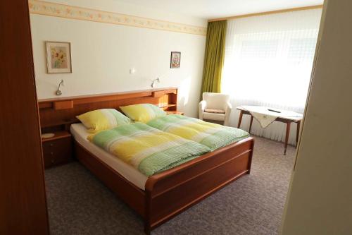 um quarto com uma cama, uma cadeira e uma janela em Gästehaus Bausch em Mehring