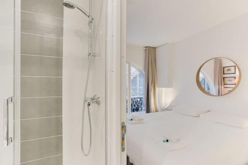 uma casa de banho branca com um chuveiro e um lavatório. em Charming House for 6 people - Louvre & Opera em Paris