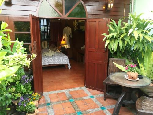 a room with a bed and a table and a door at Shanti Lodge in Bangkok