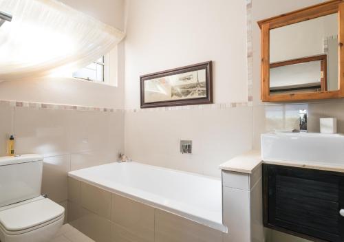 a bathroom with a tub and a toilet and a sink at Caledon 23 Country House in George