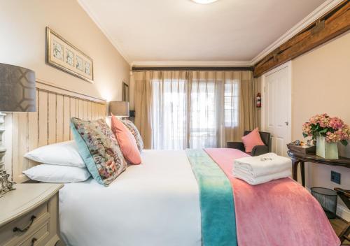 a bedroom with a large white bed with colorful pillows at Caledon 23 Country House in George