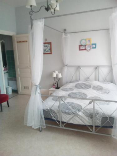 une chambre avec un lit blanc à baldaquin dans l'établissement L'Ermitage, à Pornic