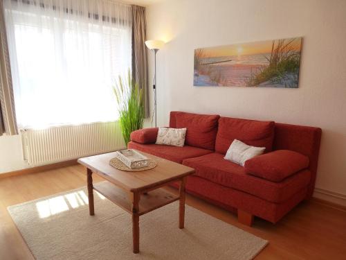 a living room with a red couch and a table at Ferienwohnungen & Bungalows Waldstraße 15 Kellenhusen in Kellenhusen
